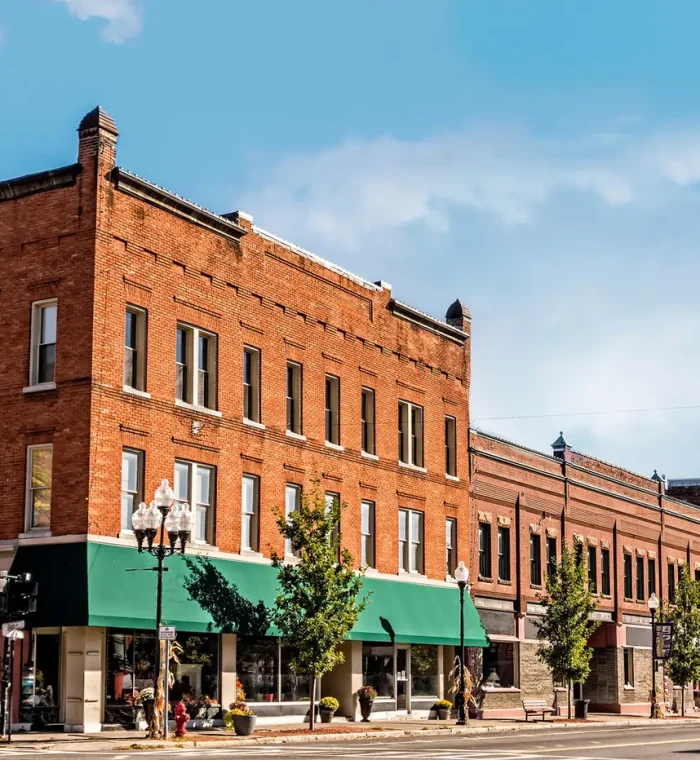 Historic brick buildings in Edgemoor, DE, featuring storefronts with green awnings and decorative planters, representing the local business district.
