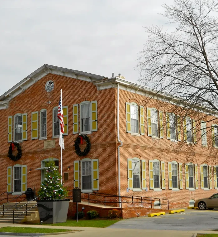 Historic brick building in Delaware City, DE, featuring yellow shutters, holiday wreaths, and a Christmas tree, representing a local landmark relevant to Nova Locksmith's community-focused services.