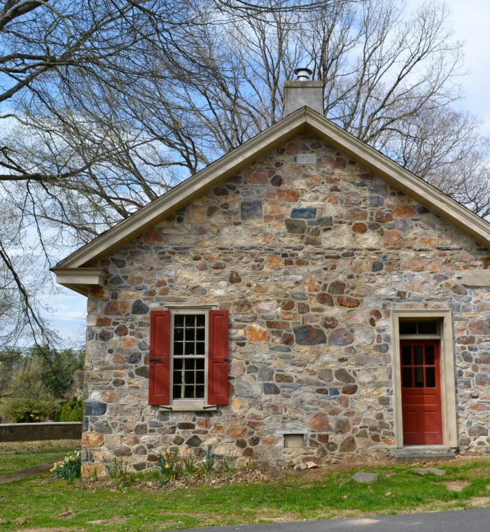 Historic stone building with red shutters and door, representing local architecture in Hockessin, DE, relevant to Nova Locksmith's community services.