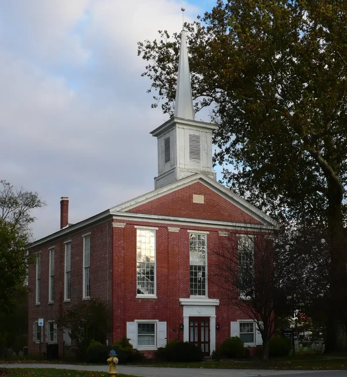Historic brick church building with a tall steeple, surrounded by trees, located in Glasgow, DE, representing community and local services.