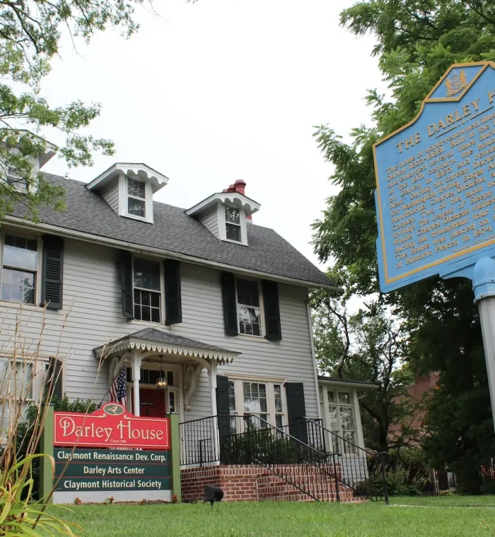 Darley House in Claymont, DE, featuring a historic building with a sign for the Darley Arts Center and Claymont Historical Society, surrounded by greenery.