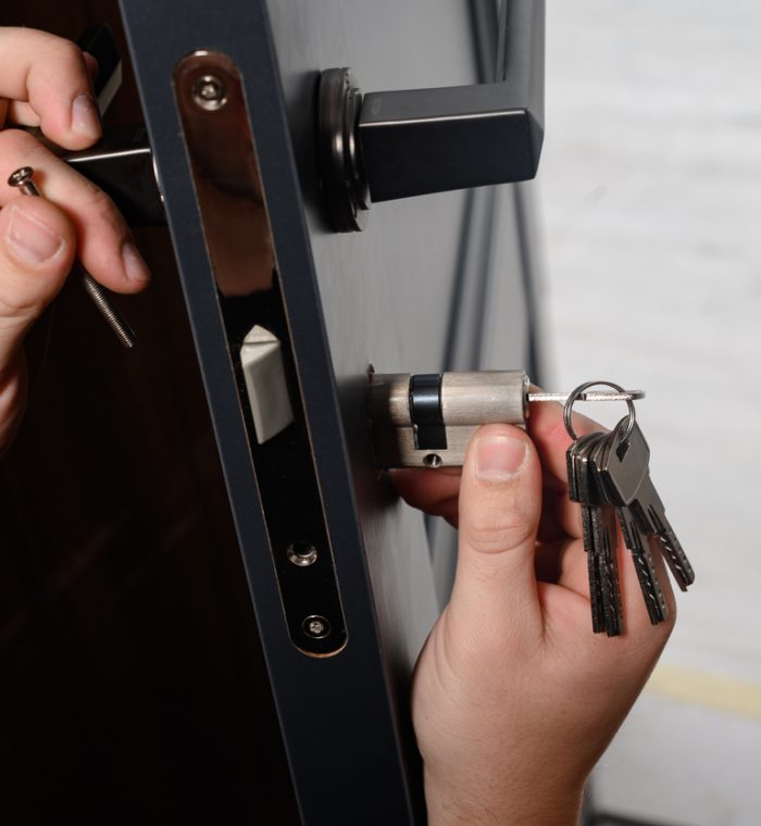 Hands installing a new lock into a door, with keys attached, illustrating Nova Locksmith's professional lock change services for enhanced security.