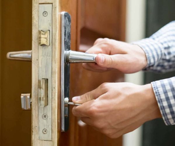close up person hand in checkered shirt opens the door  using keys