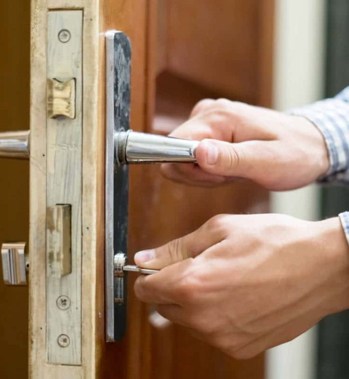 Hands inserting a key into a door lock, demonstrating secure access for businesses with master key systems.