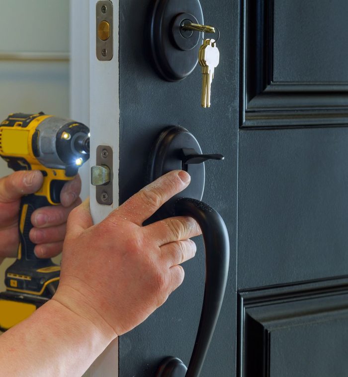 Hand installing a residential door lock with a power drill, highlighting the key and door handle, emphasizing locksmith services and security solutions.