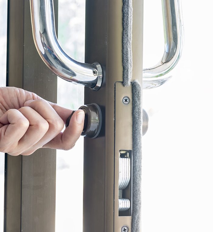 Hand using a key to unlock a commercial door lock, showcasing high-security locking mechanism relevant to Nova LockSmith's services.