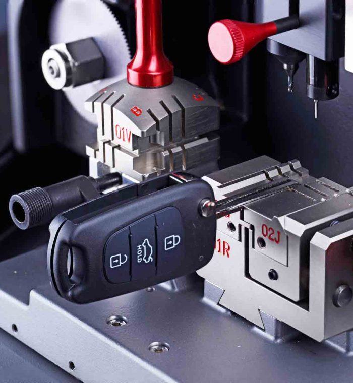 Key duplication machine with a car key in position, showcasing precision equipment for replicating keys at Nova Locksmith.