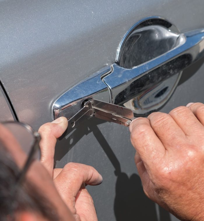 Locksmith using tools to unlock a car door, demonstrating car lockout service by Nova Locksmith.