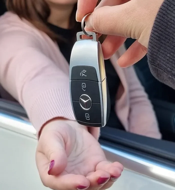 Person handing over a Mercedes car key, symbolizing lost car key replacement services by Nova Locksmith.