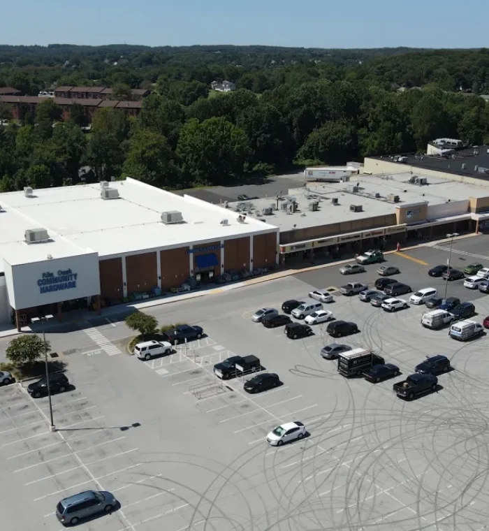 Aerial view of Pike Creek shopping center parking lot with various parked cars and surrounding greenery, highlighting Nova Locksmith's local service area in Pike Creek, DE.